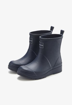 Paar schwarze, knöchelhohe Gummiregenstiefel mit Zuglaschen und Markenetikett vorne, nebeneinander auf weißem Hintergrund präsentiert.