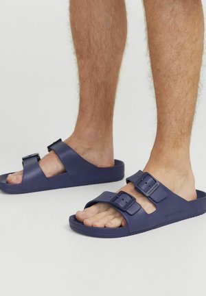 Sandalias de color azul marino de material sintético, con dos correas ajustables y un diseño de punta abierta. Suela texturizada para mayor agarre.