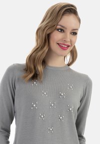 Pulover gri cu guler rotund, împodobit cu accente de perle în modele de stea pe față. Textură moale, tricotată.