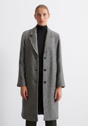 Black and white houndstooth coat with a notched collar, double-breasted buttons, and long sleeves, textured fabric finish.