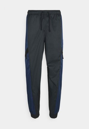 Pantalon de jogging athlétique noir et bleu marine avec ceinture élastique, cordon de serrage, poches latérales zippées et poignets élastiques.