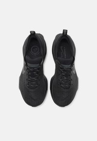 Scarpe sportive nere con una tomaia in tessuto testurizzato, lacci piatti e un logo minimal. Presentano un colletto imbottito e un design della suola con ammortizzazione.