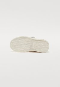 Suela de zapato blanca con una superficie texturizada, que presenta un patrón de diamante para mayor agarre y un acento rectangular en el centro.