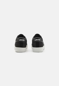 Schwarze Levi's Sneaker mit weißen Gummisohlen, die ein strukturiertes Obermaterial, flache Schnürsenkel und ein Markenlabel an der Ferse aufweisen.