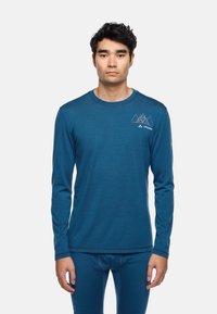 Langärmliges Oberteil in Teal, aus weichem Stoff gefertigt. Verfügt über einen runden Ausschnitt, eine dezente Berggrafik und kontrastierende Nähte.