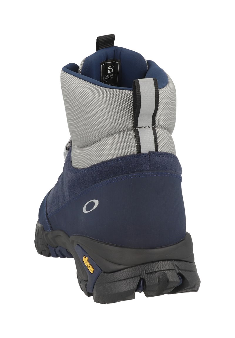 Scarponcino da trekking blu navy con tomaia grigia in materiale sintetico, suola in gomma e tallone rinforzato. Presenta un gancio per il trasporto e dettagli testurizzati.