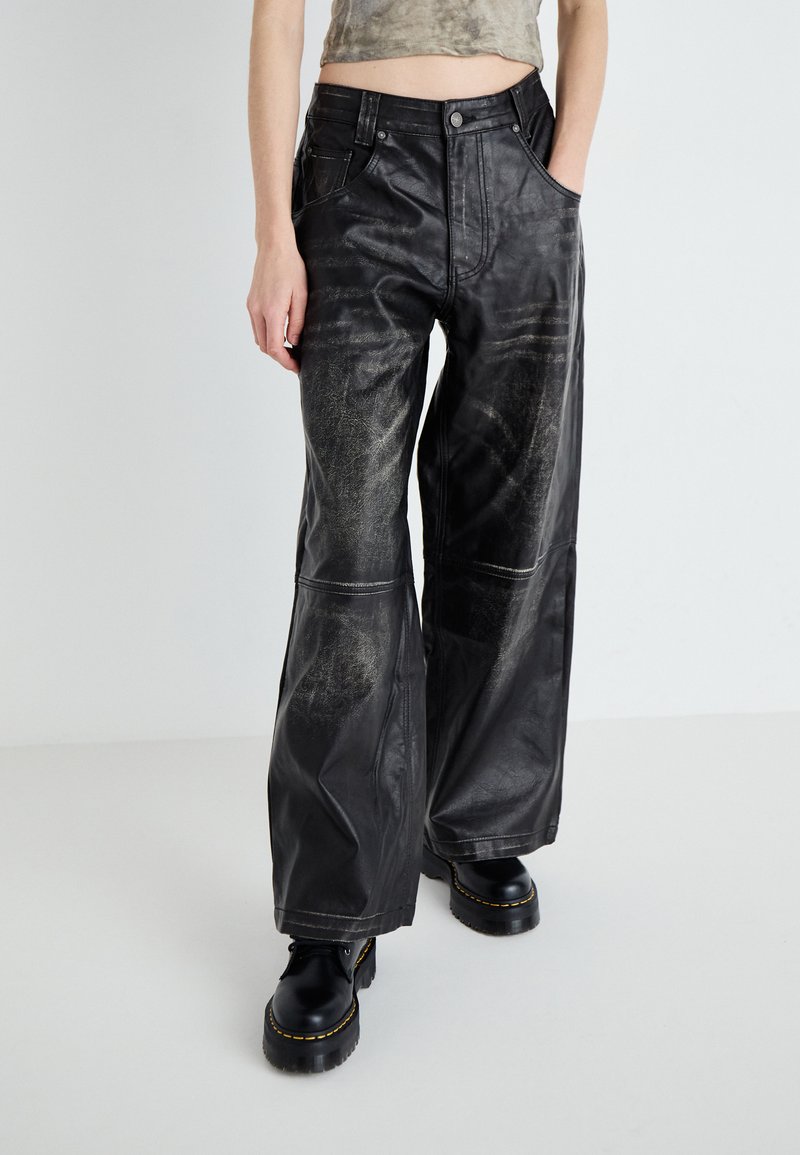 Pantaloni largi din piele neagră cu textură uzată, dotati cu buzunare frontale și cusături contrastante. Asortați cu cizme chunky negre.