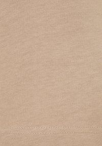 Beige cotton fabric with a soft texture, featuring a smooth knit design and clean stitch detailing along the hem.