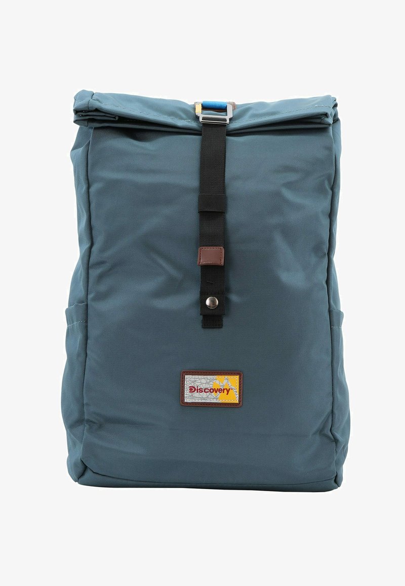 Mochila de tela azul con un diseño de parte superior enrollable, asegurada por una correa negra y un hebilla. Presenta una etiqueta de cuero marrón con la palabra "Discovery."