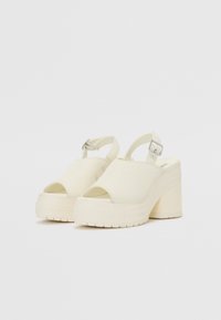 Sandales à plateforme épaisses en toile crème. Conception à bout ouvert, bride de cheville réglable avec boucle en argent, semelle en caoutchouc texturée.