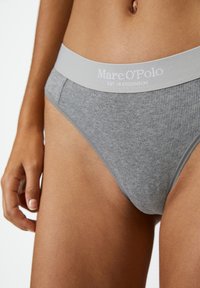 Graue gerippte Baumwollunterhose mit einem breiten grauen elastischen Bund, der weißen Text "Marc O'Polo EST. IN STOCKHOLM." zeigt. Nahaufnahme von der Seite.