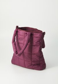 Lilla quilts tote bag med to håndtak og glidelås. Myk, polstret tekstur med rektangulær form og firkantede mønsterdetaljer.