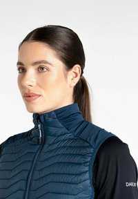 Marineblauer gesteppter Weste mit hohem Kragen, ausgestattet mit einem Reißverschluss vorne, eleganter Textur und taillierter Passform. Weicher Stoffüberzug an den Schultern und Armausschnitten.
