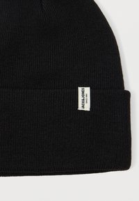 Μαύρο πλεκτό σκουφί με ριμπ ύφανση και διπλωμένο τελείωμα, που διαθέτει μια μικρή λευκή ετικέτα στο πλάι με λεπτομέρειες της μάρκας.