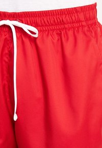 Röda shorts i lättviktig tyg med en mjuk textur, med elastisk midja och vit dragsko.