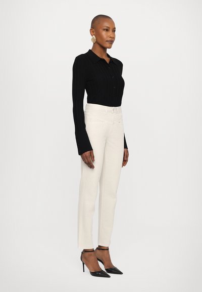 Black ribbed long-sleeve shirt withbutton-down collar, paired with high-waisted white jeans and black pointed-toe heels.