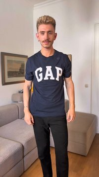 T-shirt azul marinho com grandes letras brancas "GAP", mangas curtas e um corte descontraído, combinado com calças pretas. A textura parece suave.