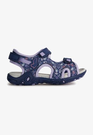 Sandalias moradas y navy con patrón floral, correas ajustables de velcro, diseño abierto en la punta y suela de goma texturizada con acentos de agarre.