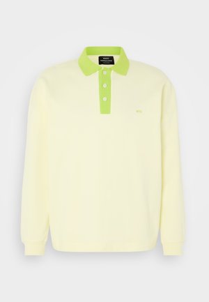 Polo de manga longa amarelo-claro com colarinho verde e fileira de botões. Apresenta um discreto logotipo "MN" no peito. Material de algodão suave.