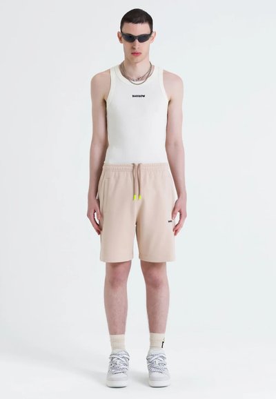 Top cu bretele albă, texturat, cu logo-ul "BARROW", pantaloni scurți bej cu șnur și buzunare, accente galbene, asortați cu adidași albi și ochelari de soare negri.