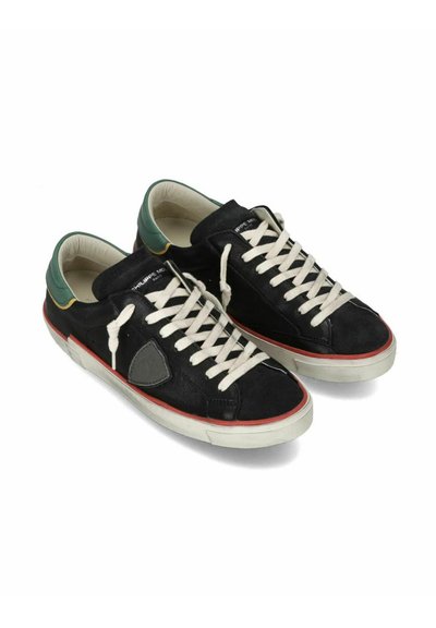 Sorte ruskind sneakers med en grøn og gul hæl, hvide snørebånd, rød såleaccent og en tekstureret grå logo detalje på siden.