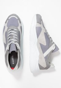 Baskets grises en suède et mesh, avec une semelle blanche, des accents gris clair et un motif texturé sur la tige.