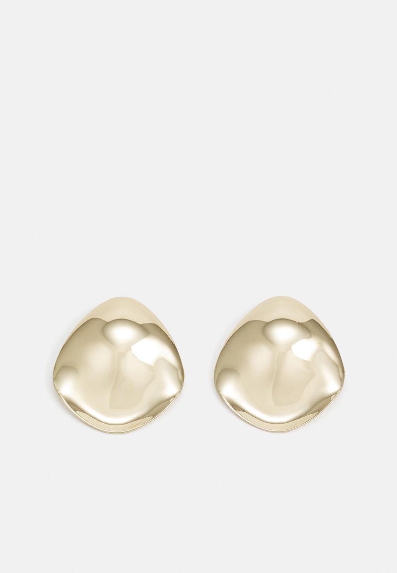 Boucles d'oreilles en métal doré au fini lisse, avec une forme abstraite courbée. La surface polie reflète la lumière, créant des reflets et des ombres subtils.