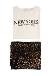 Wit T-shirt met de tekst "NEW YORK" in zwarte letters, gecombineerd met zwarte en bruine luipaardprint broek met een zwarte tailleband met strik.