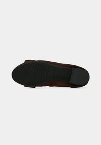 Semelle de chaussure en daim marron avec une semelle extérieure en caoutchouc noir texturé. Présente un bout arrondi et un design minimaliste.