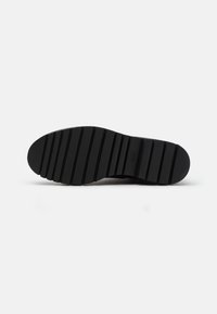 Suola nera di scarpa con un motivo testurizzato, caratterizzata da scanalature orizzontali e una punta arrotondata. Materiale resistente, progettato per trazione e stabilità.
