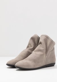 Stivaletti in suede grigi con una texture liscia, punta tonda e design minimalista, dotati di suola in gomma nera e leggeri accenti di cucitura.