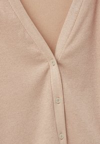 Żakiet prążkowany w miękkim różowym materiale z dekoltem w serek, z pięcioma guzikami z przodu i subtelnym połyskiem w fakturze.