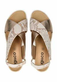 Sandačky s křížovými popruhy ve světle béžové barvě s hadím vzorem, s kovovým zlatým akcentem a polstrovanou stélkou.