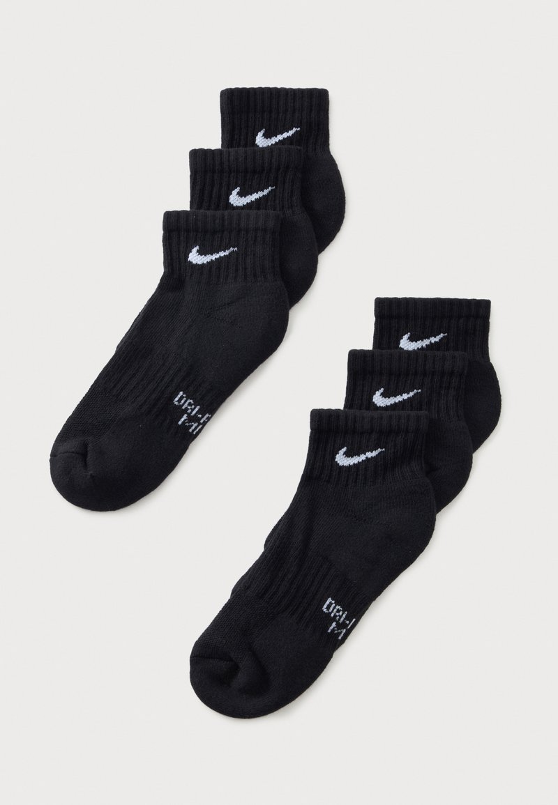 Έξι μαύρες κάλτσες αστραγάλου Nike με λευκά λογότυπα swoosh, τοποθετημένες σε δύο σειρές των τριών ζευγαριών σε ανοιχτό φόντο.