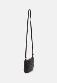 Bolso cruzado negro acolchado con una forma rectangular delgada, que presenta una textura de cuero suave y un acento de hardware en tono dorado en la cremallera.