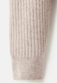 Cuff a coste di un beige chiaro con una consistenza morbida, caratterizzato da un motivo a maglia stretta e un bordo leggermente svasato sul fondo.