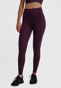 Lila, hoch-taillierte Leggings mit glatter Textur und figurbetontem Design, die ein dezentes Markenlogo am Bund und an den Fußleisten haben.
