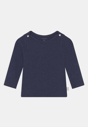 Chemise à manches longues bleu marine en tissu côtelé, avec un col rond, deux boutons-pression blancs à l'épaule et un petit logo.