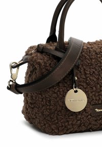 Bolso de mano de textura marrón con un exterior difuso, asas de cuero, una correa de hombro desmontable y una etiqueta de metal redonda con logo.