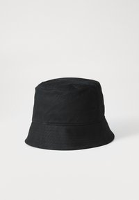 Cappello a secchiello in cotone nero con corona arrotondata e ampia visiera flessibile. Presenta due fori di ventilazione sui lati e una texture liscia.