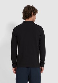 Zwarte langemouwen shirt met een textuurafwerking, klassieke kraag en rechte zoom, gedragen over marineblauwe textuurbroek.