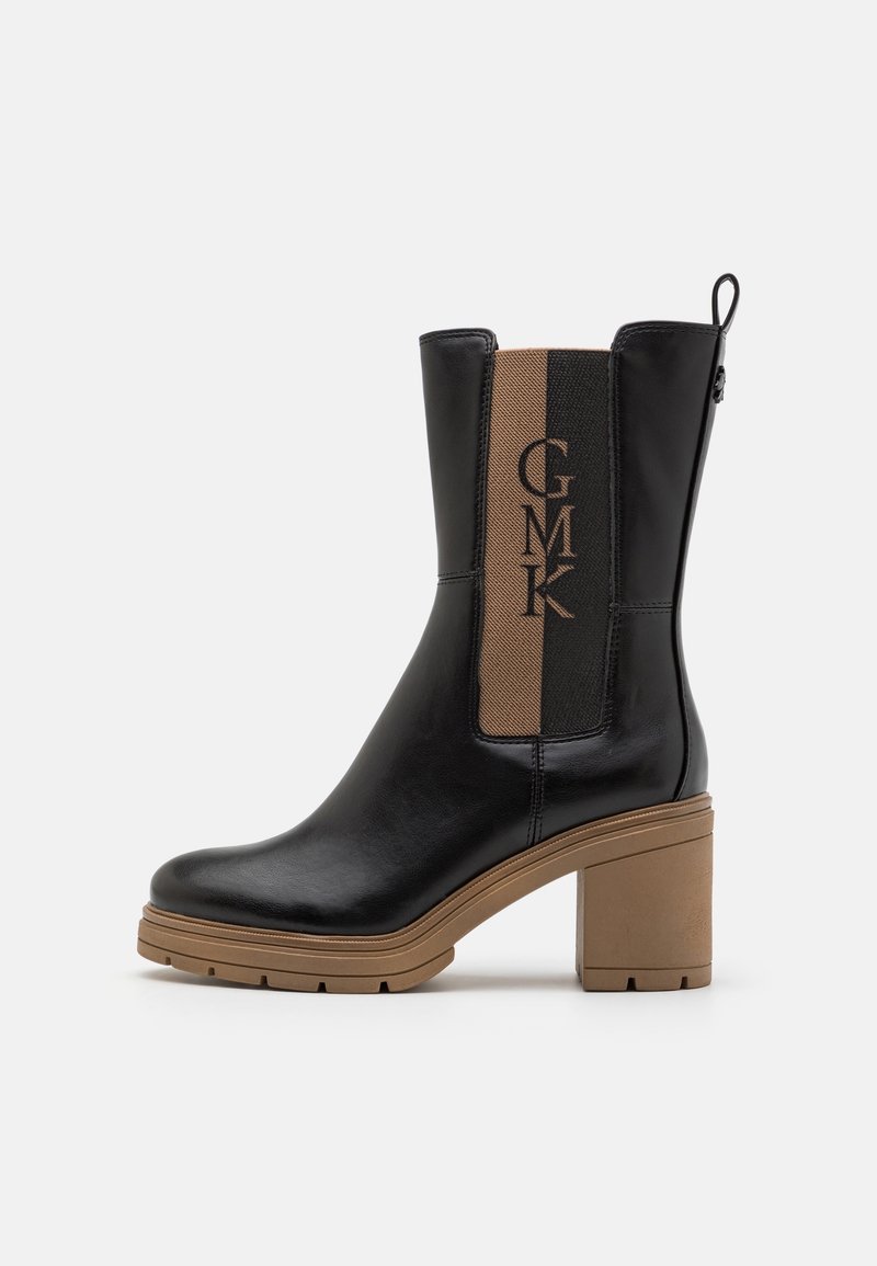 Bottine en cuir noir avec talon carré marron et panneau latéral élastique arborant le logo vertical GMK en noir et marron.