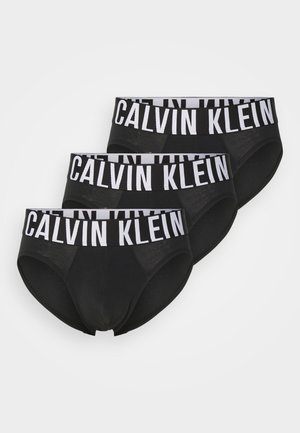 Tre par sorte bomuldsunderbukser med en hvid elastisk talje, hvor "CALVIN KLEIN" er trykt med fede bogstaver.