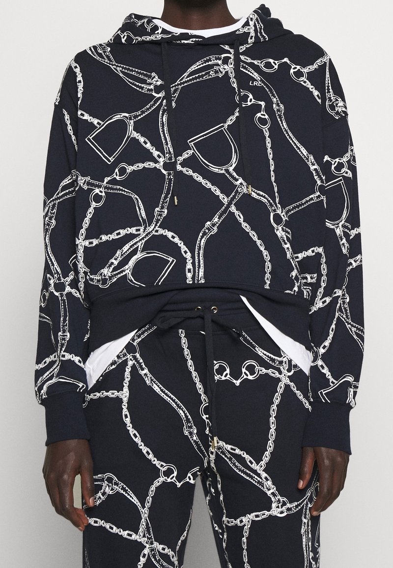 Marinblå hoodie med vitt kedjemönster, dragsko i luvan, känguruficka och ribbade ärmslut. Mjuk tyg med avslappnad passform, passar bra med matchande byxor.