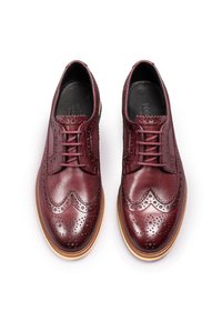 Bordeaux læder brogues med dekorative perforeringer, bølgede kanter og en lys brun gummisål. Snørelukning med tonede snørebånd.