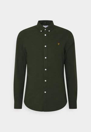 Donkergroene langsluitende blouse van katoen, met een klassieke kraag, witte knopen en een klein geel logo op de borst.