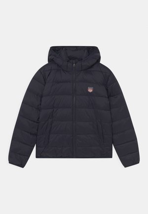 Veste noire matelassée à capuche avec fermeture éclair à l'avant et petit écusson rouge, blanc et bleu du logo GANT sur la poitrine gauche.