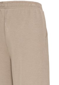 Pantalon de survêtement beige avec taille élastique et poches latérales, présenté de la taille jusqu'à mi-cuisse sur un fond blanc.