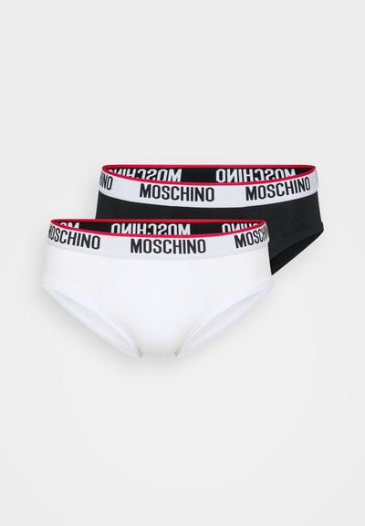 Zwei Paar Slips: ein weißes und ein schwarzes. Beide verfügen über einen breiten Gummibund mit der Markenbezeichnung "Moschino" in fetten schwarzen Buchstaben.