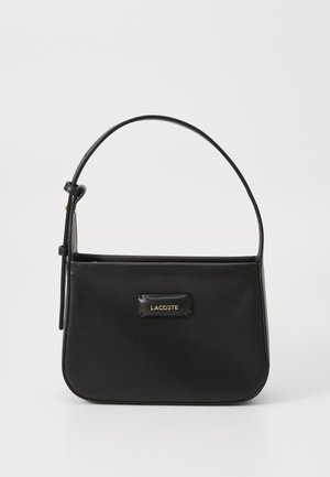 Black leather handbag with a structured shape, featuring a gold Lacoste logo plate, slim strap, and smooth texture.